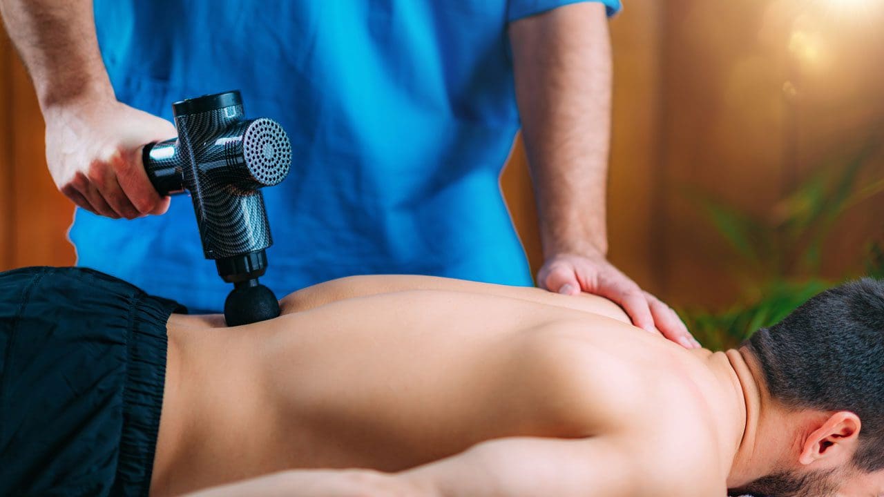 https://wellnessdoctorrx.com/wp-content/uploads/2021/04/massage-gun-treatment-physical-therapist-massaging-EESEKKK_02.jpg